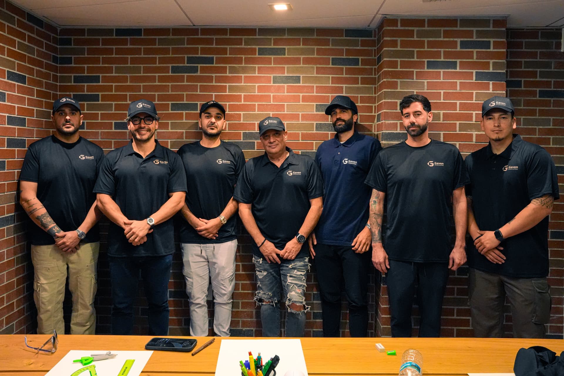 The Gaven Constructions team in branded shirts and caps beside a table of drawing tools