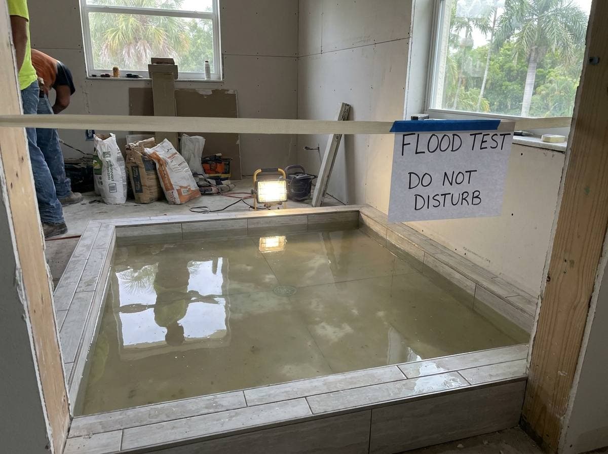 Bathroom waterproofing inspection in progress — flood test on tile shower floor before finish setting