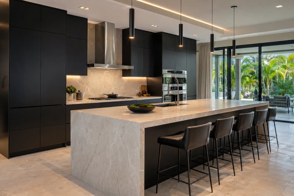 Kitchen with matte black cabinets, a waterfall quartz island and sliders to a palm-lined patio