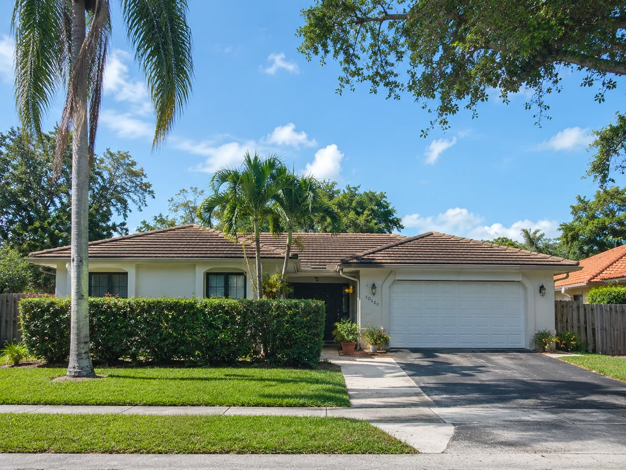 Single-story stucco CBS ranch home with a barrel-tile roof, two-car garage and framing palms