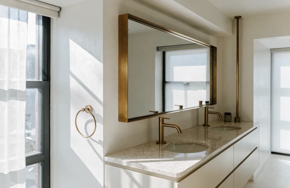 Can you live in a Miami condo during a renovation: a finished bathroom with a floating double vanity, brass faucets and a full-height window.